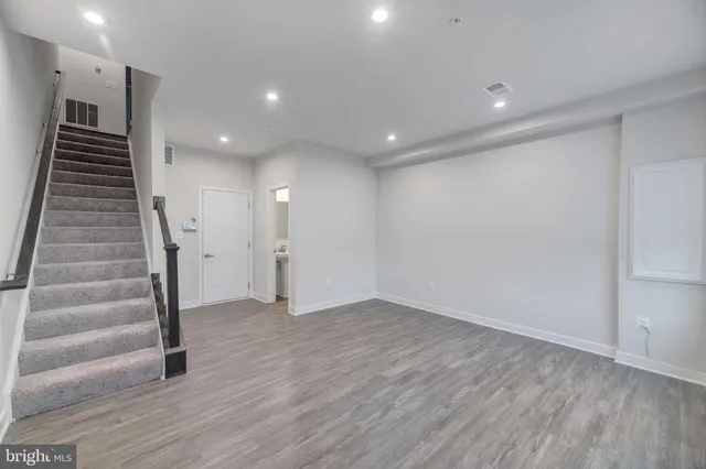 a view of an empty room with stairs and wooden floor