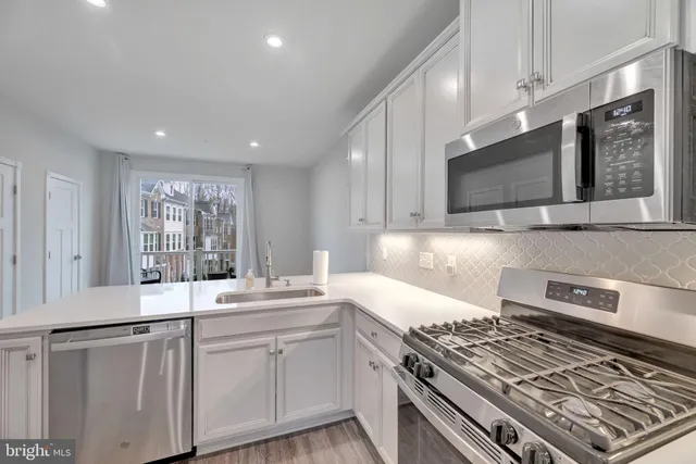 a kitchen with stainless steel appliances granite countertop a stove a sink and a microwave