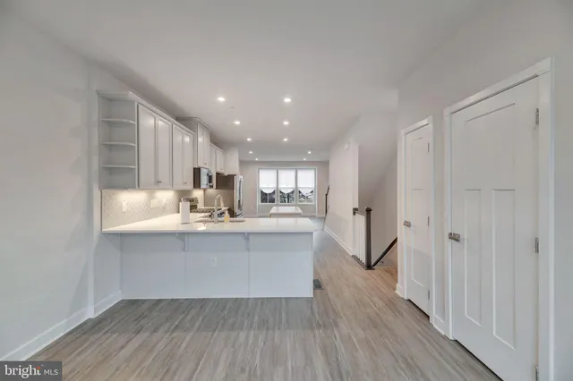 a large white kitchen with wooden floor and a sink
