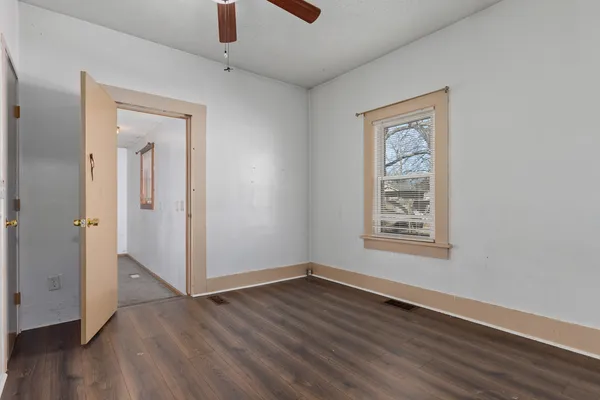 an empty room with wooden floor cabinet and windows