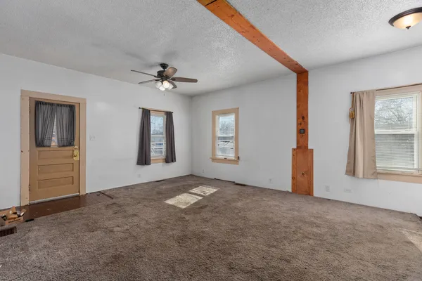 an empty room with windows and chandelier fan