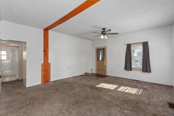 an empty room with windows and fan