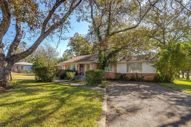 a view of a house with a big yard and large trees