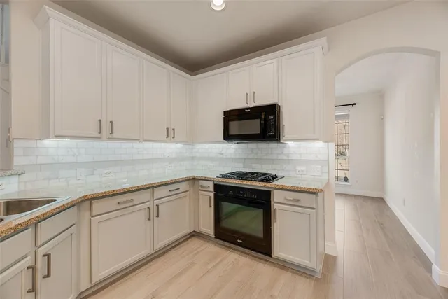 a kitchen with stainless steel appliances granite countertop a stove a sink and a microwave