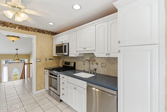 a kitchen with granite countertop a sink a stove and refrigerator