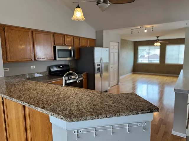 a kitchen with kitchen island granite countertop a sink a counter top space cabinets and stainless steel appliances