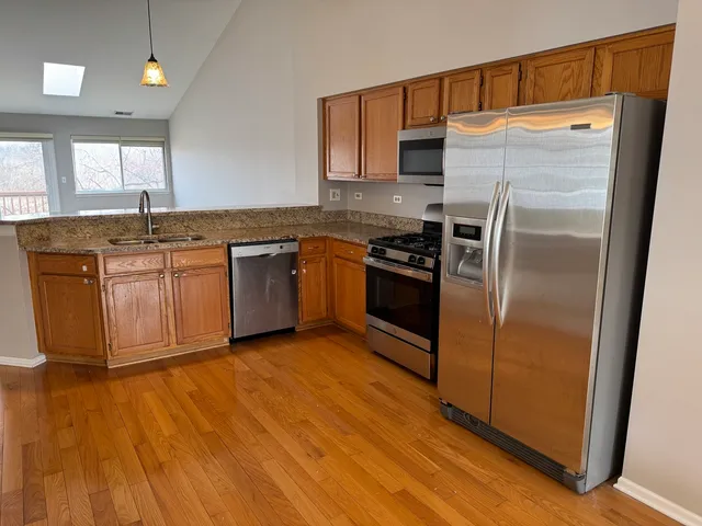 a kitchen with stainless steel appliances granite countertop a refrigerator a sink and a stove