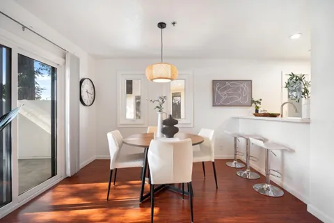 a dining room with wooden floor a glass table and chairs