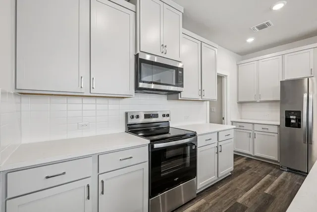 a kitchen with kitchen island a sink stainless steel appliances and white cabinets
