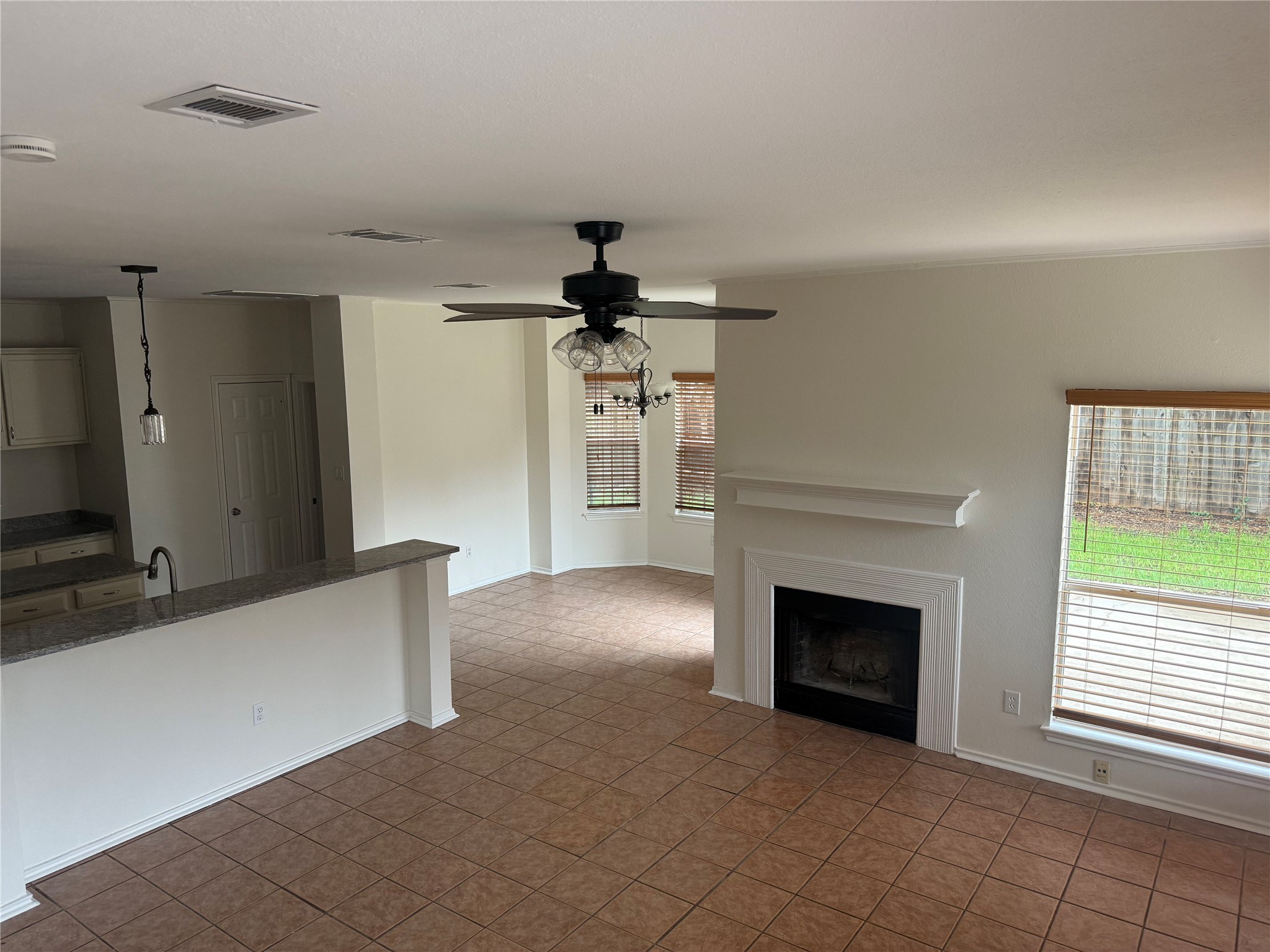 16910 Isle Of Man Road Pflugerville, TX 78660 - Photo 3 of 13 Expansive room featuring a white fireplace with mantle, ceramic tile flooring, and multiple windows with blinds