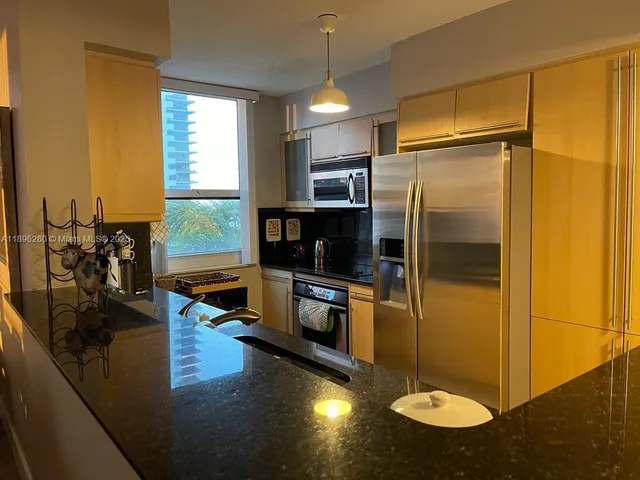 a kitchen with stainless steel appliances granite countertop a refrigerator a stove and a sink with granite countertops