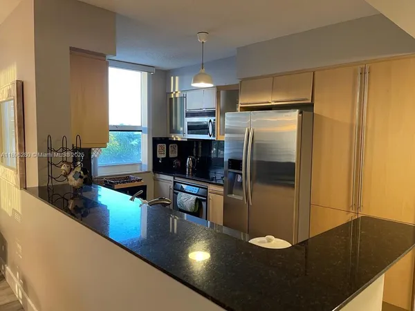 a kitchen with stainless steel appliances granite countertop a refrigerator a stove and a sink with wooden floor