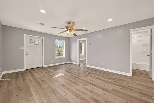 a view of an empty room with window and wooden floor