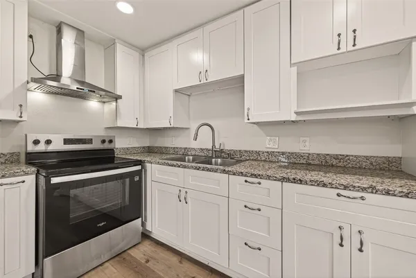 a kitchen with granite countertop white cabinets and stainless steel appliances