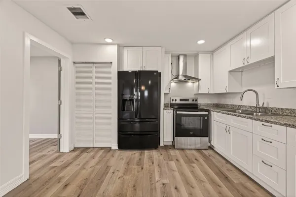 a kitchen with granite countertop a refrigerator and a stove top oven