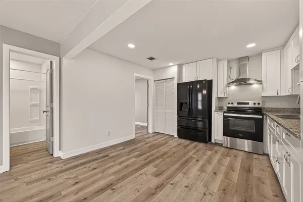 a kitchen with granite countertop a refrigerator and a stove top oven