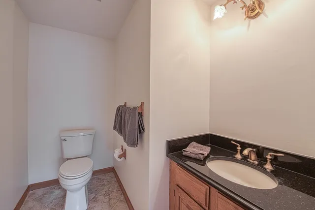 a bathroom with a granite countertop sink and a toilet