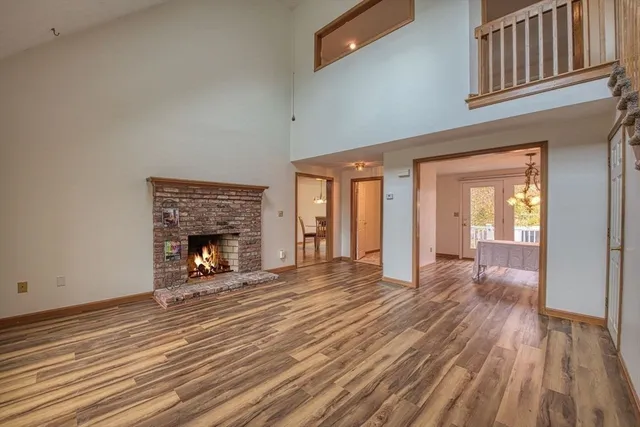 a view of an empty room with wooden floor fireplace and a window