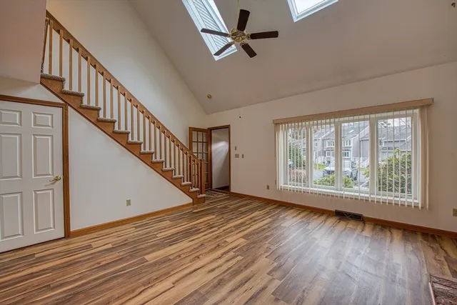 a view of an empty room with wooden floor and fan