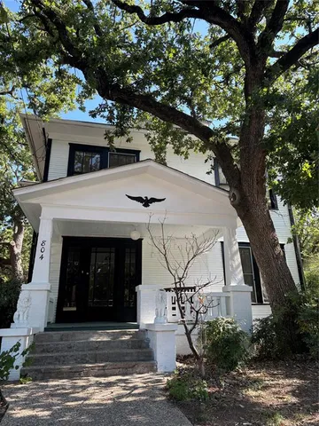 a view of a white house with a large tree