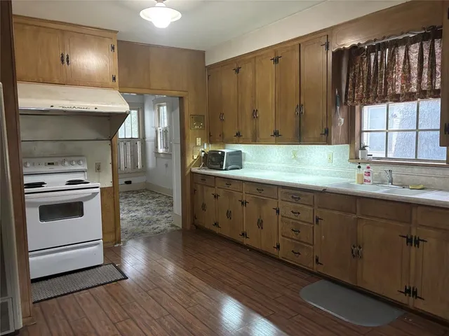 a kitchen with granite countertop a stove a sink and dishwasher with wooden floor