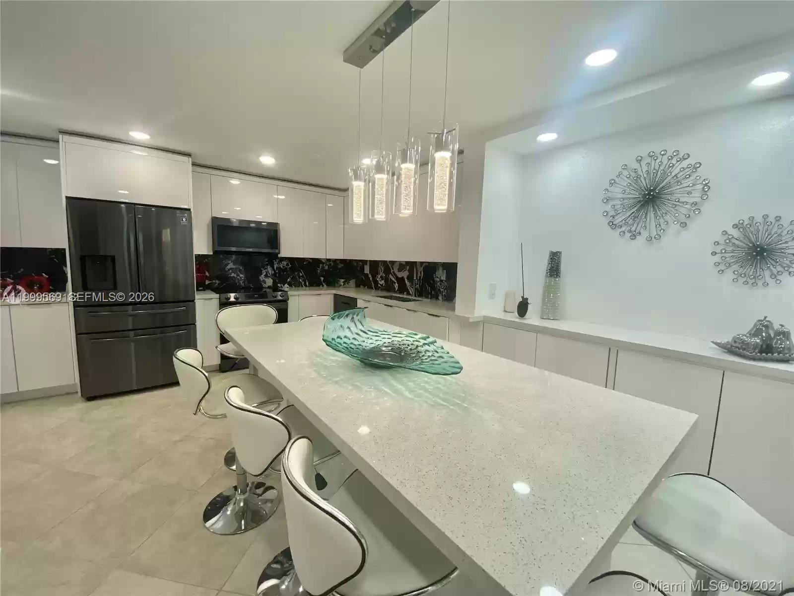 6841 Southwest 147th Avenue, Unit 2H Miami, FL 33193 - Photo 11 of 22 a kitchen with a table chairs refrigerator and microwave