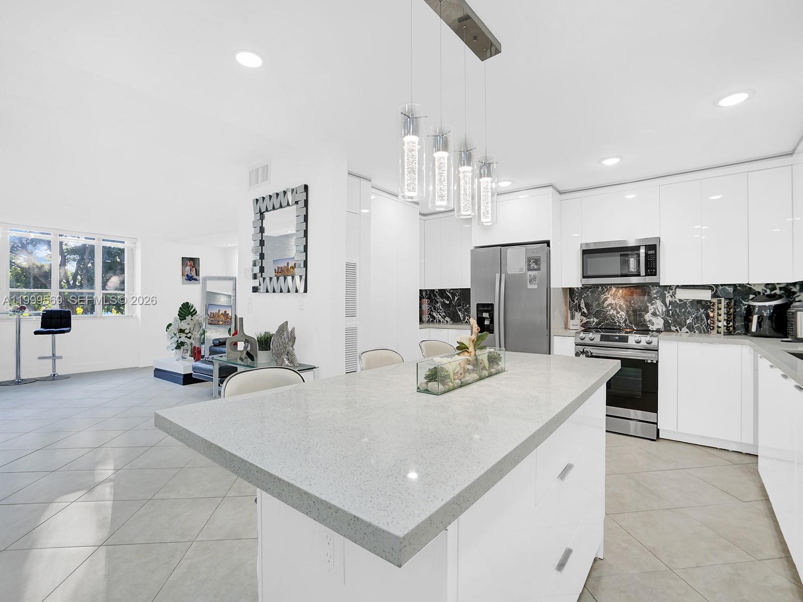 6841 Southwest 147th Avenue, Unit 2H Miami, FL 33193 - Photo 12 of 22 a kitchen with kitchen island a white cabinets and refrigerator