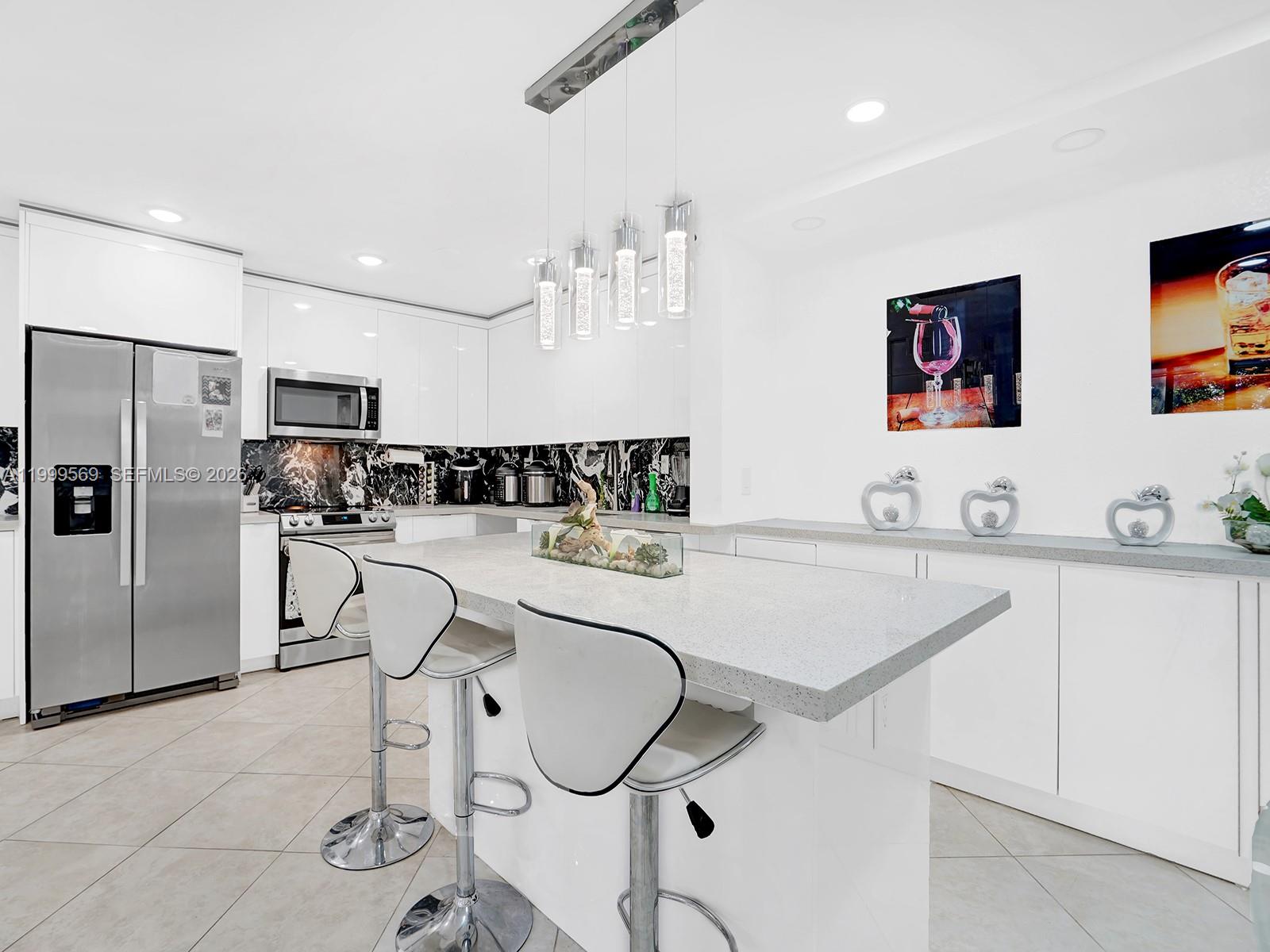 6841 Southwest 147th Avenue, Unit 2H Miami, FL 33193 - Photo 9 of 22 a kitchen with stainless steel appliances granite countertop a sink a stove a refrigerator with white cabinets and couches