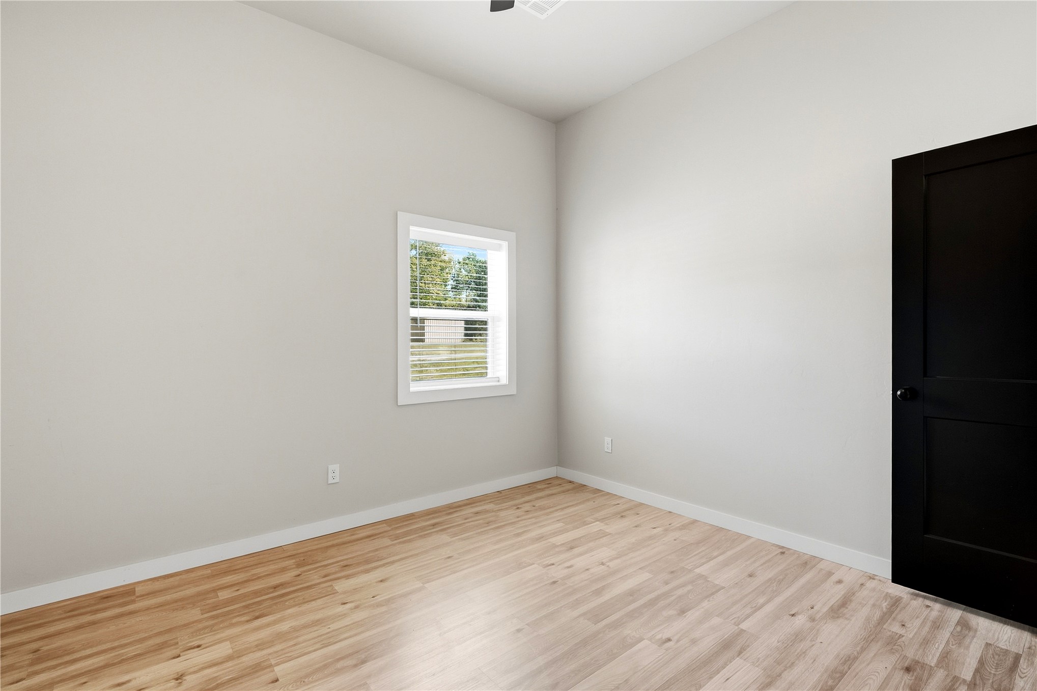 420942 East 1168 Road Eufaula, OK 74432 - Photo 35 of 43 Wood-finish flooring, white walls, black paneled door, and a white-framed window. Cordless Plantation blinds.