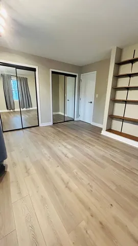 a view of an empty room with window and wooden floor