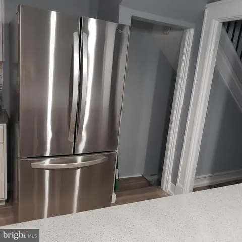 a view of a refrigerator in kitchen and stainless steel appliances wooden floor
