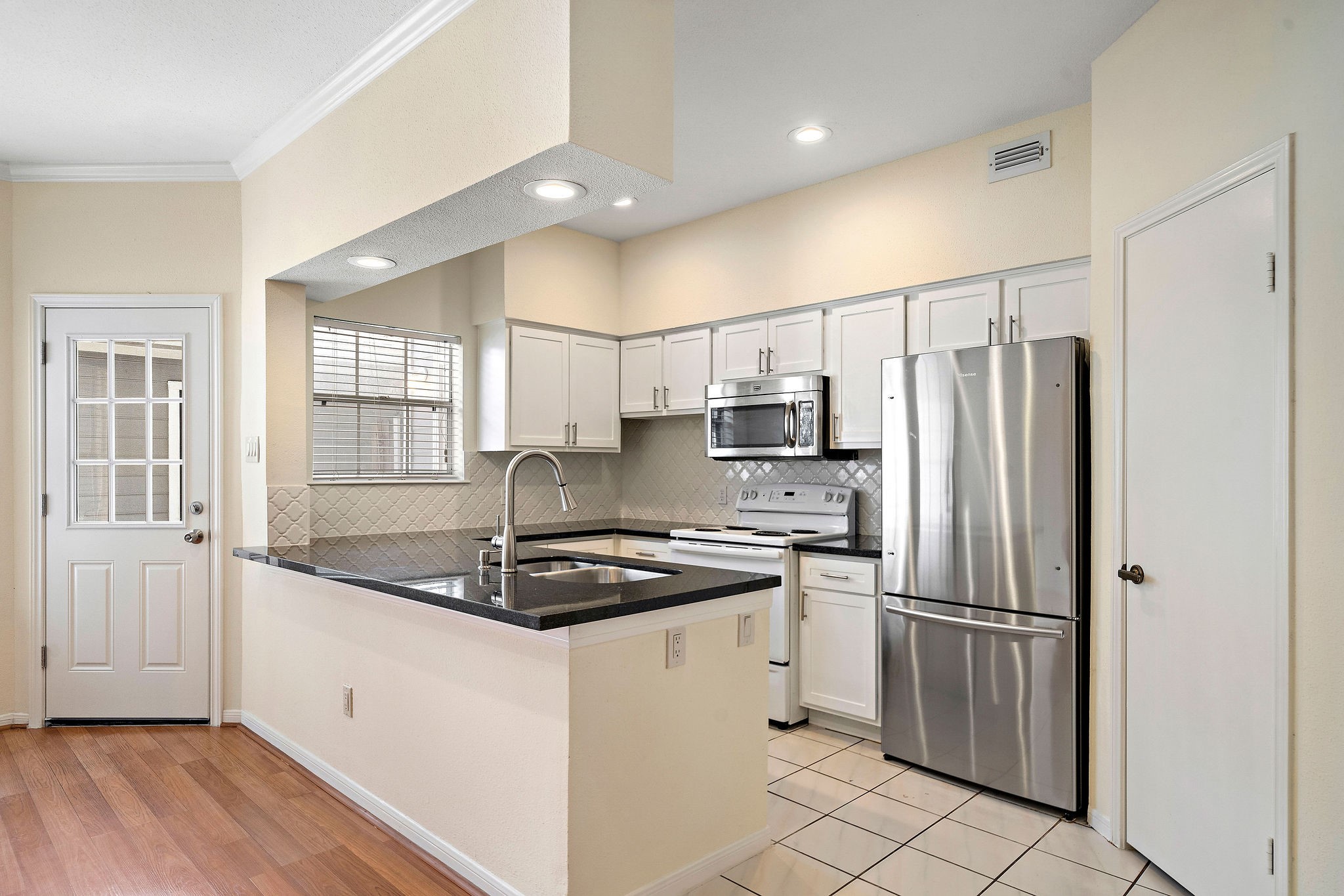 7941 Knight Road, Unit 20 Houston, TX 77054 - Photo 2 of 11 Updated kitchen with granite countertops, white cabinetry, decorative tile backsplash and walk in pantry.