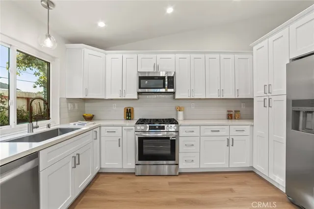 a kitchen with stainless steel appliances granite countertop a stove and white cabinets