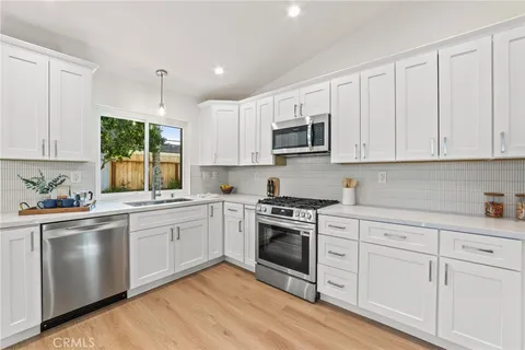 a kitchen with cabinets appliances a sink and a window