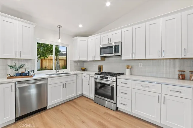 a kitchen with cabinets appliances a sink and a window