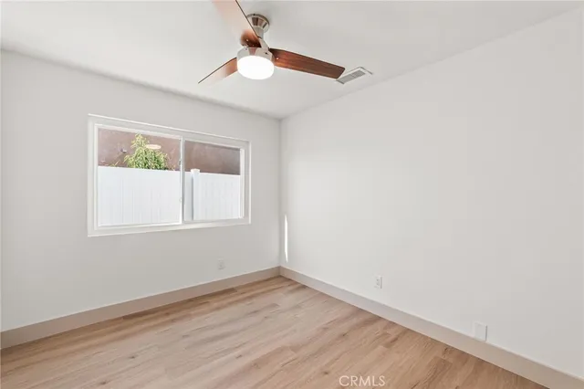 an empty room with wooden floor fan and window