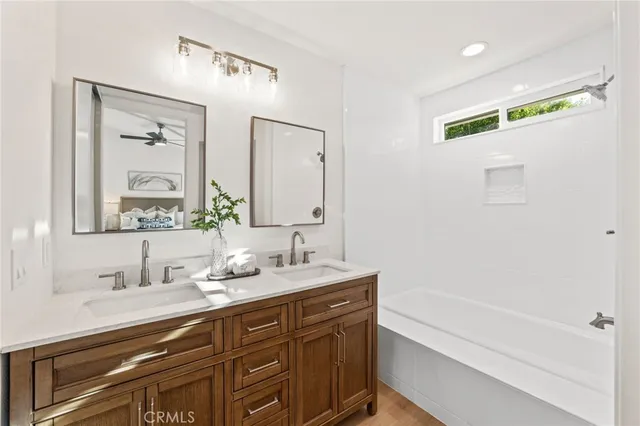 a bathroom with a double vanity sink a mirror and a bathtub