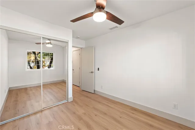 an empty room with wooden floor chandelier fan and windows