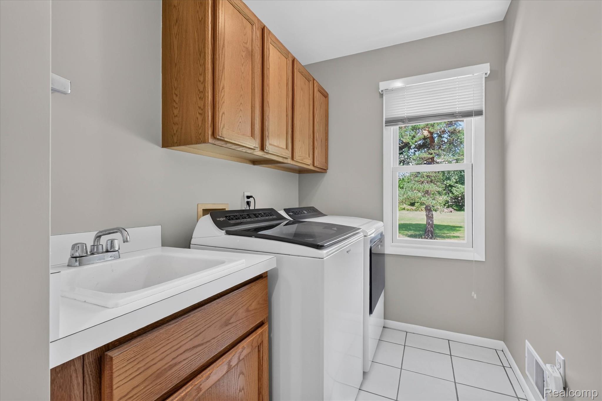 4037 Chilson Road Howell, MI 48843 - Photo 13 of 69 Utility room featuring wood-finish cabinetry, a single basin sink, white countertop, and a window for natural illumination