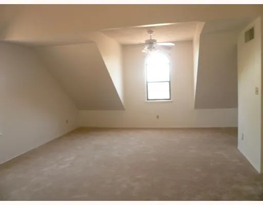 an empty room with windows and fan