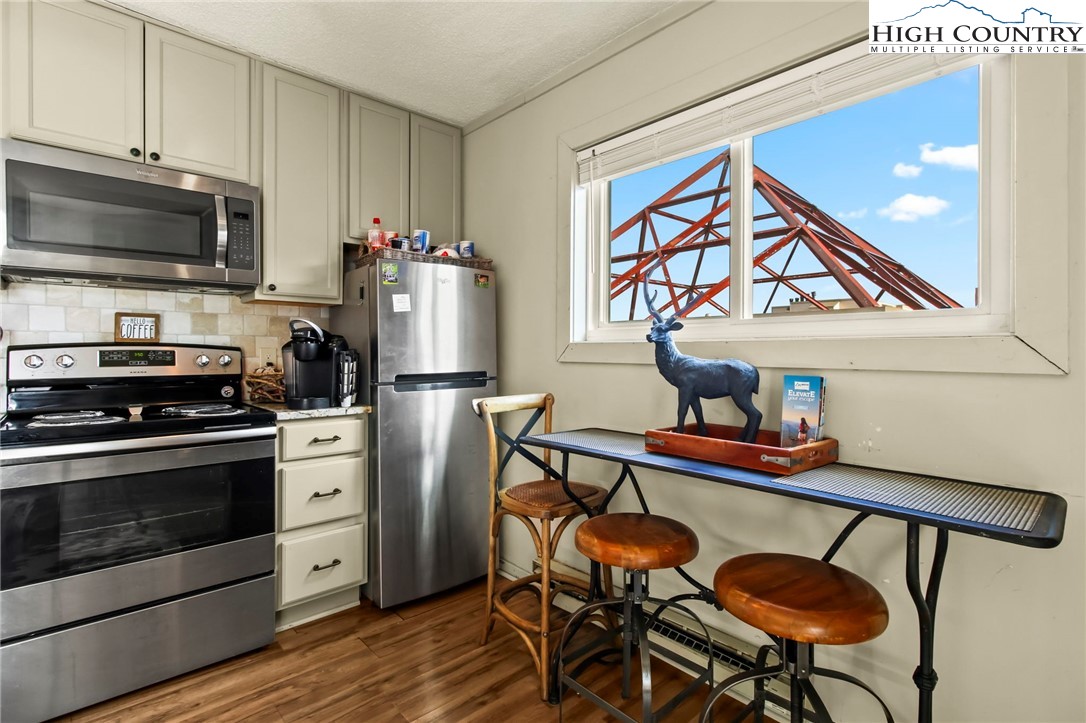 301 Pinnacle Inn Road, Unit 3301 Beech Mountain, NC 28604 - Photo 8 of 18 a kitchen with stainless steel appliances a stove a refrigerator and a dining table with wooden floor