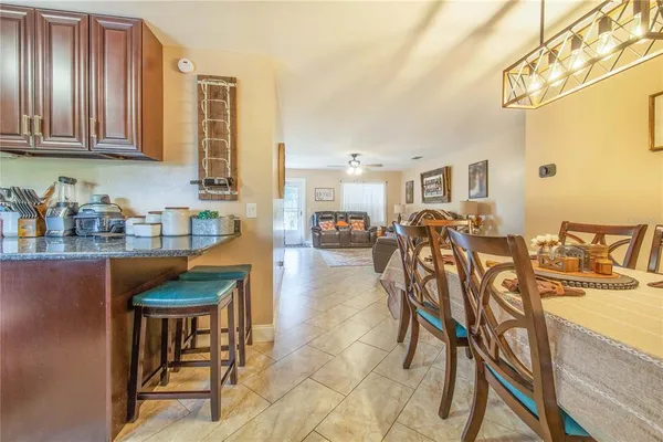a dinning area with stainless steel appliances granite countertop a table chairs and a refrigerator