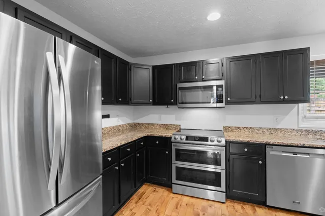 a kitchen with stainless steel appliances granite countertop a refrigerator stove and microwave