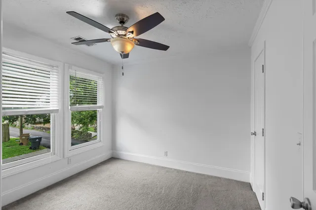 an empty room with windows and ceiling fan