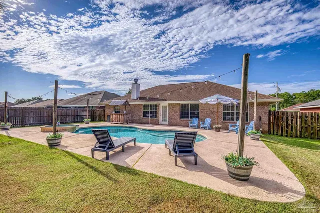 a view of a backyard with swimming pool and sitting area