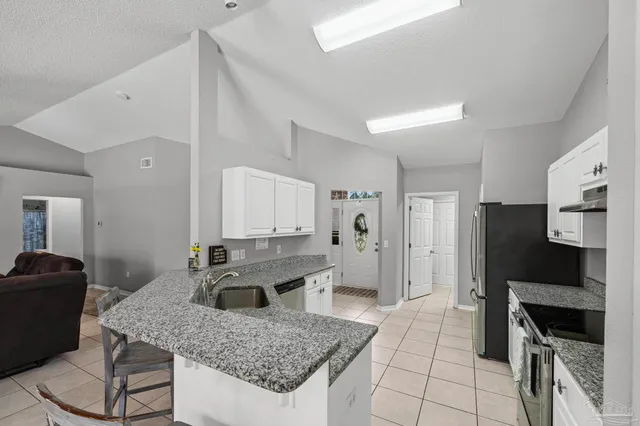 a kitchen with granite countertop a sink stove and cabinets