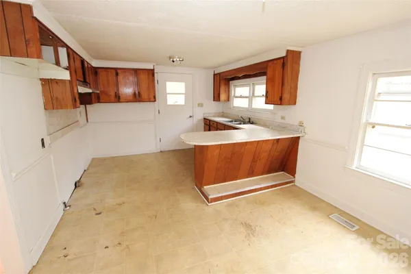 an empty room with wooden floor fireplace and windows