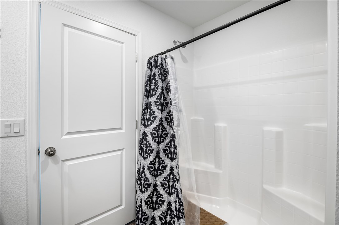 3623 East Andrea Drive Kingman, AZ 86409 - Photo 25 of 40 Bathroom featuring a white shower with an integrated shelf, a white door with a round door handle, and white light switches