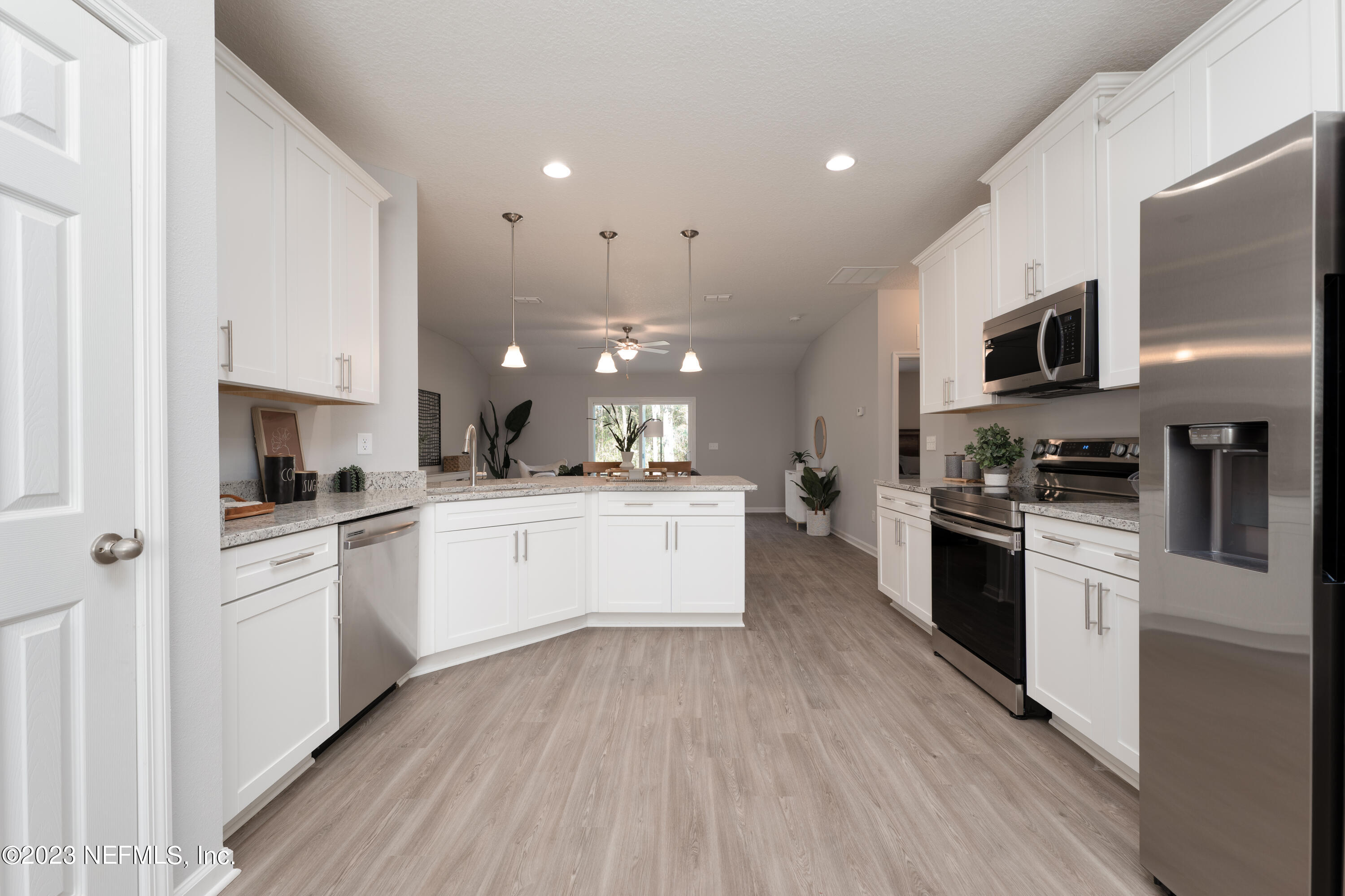 12701 Dunn Creek Road Jacksonville, FL 32226 - Photo 12 of 51 a kitchen with stainless steel appliances white cabinets a sink a stove a microwave and wooden floors