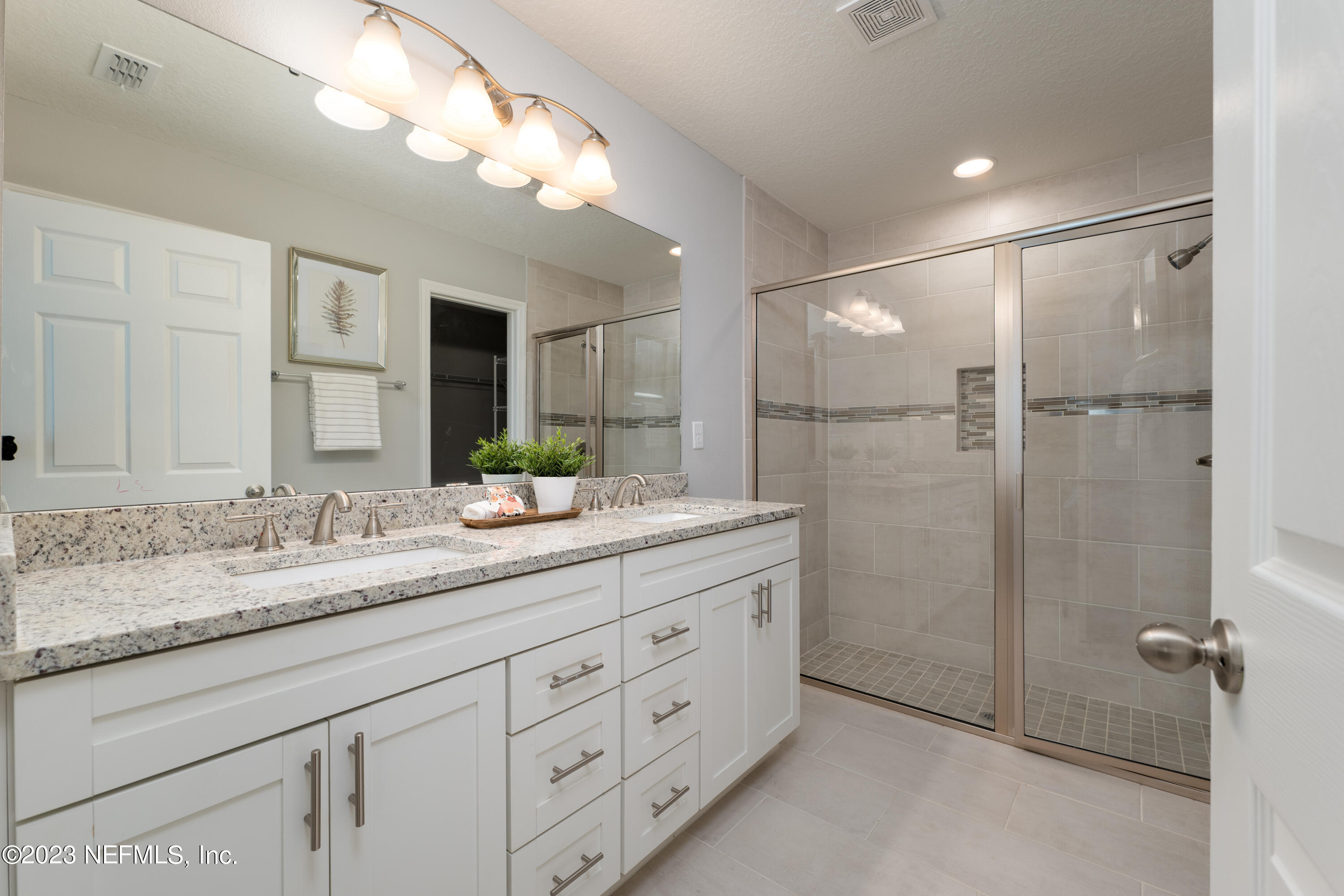 12701 Dunn Creek Road Jacksonville, FL 32226 - Photo 26 of 51 a bathroom with a granite countertop sink a mirror and a shower